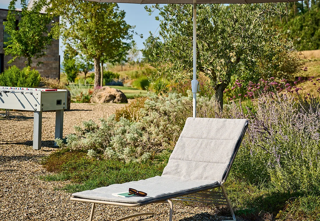 Sommerterrasse mit Liegen, Polstern und Sonnenschirm